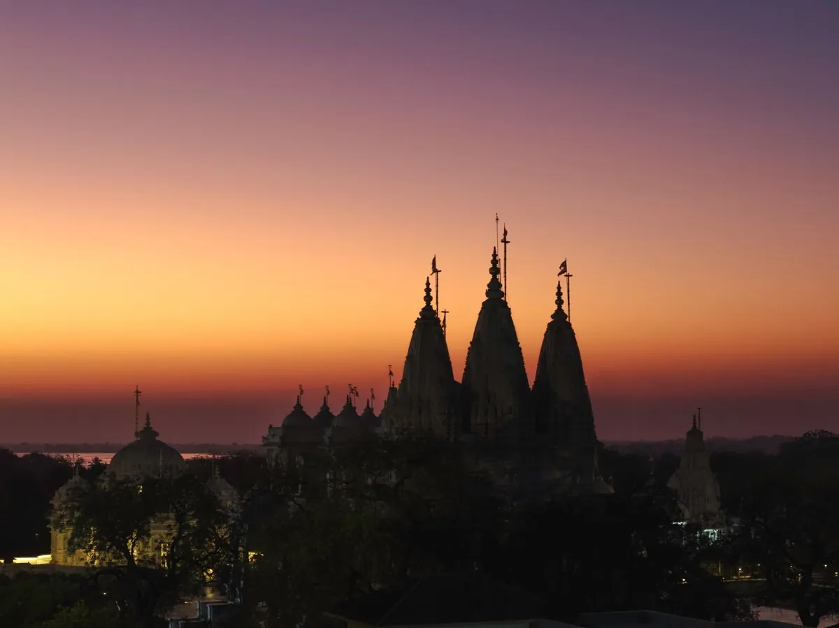 Mandir spires silhouetted against a glowing dusk sky